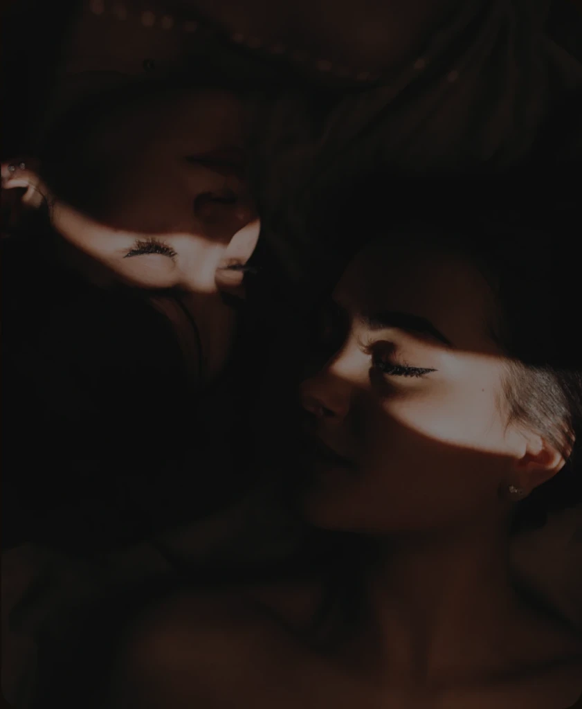 Two women resting close together in warm light and shadow