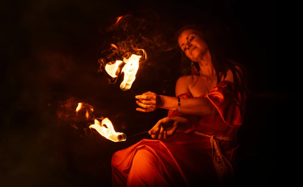 Woman in a red dress performing with fire at night