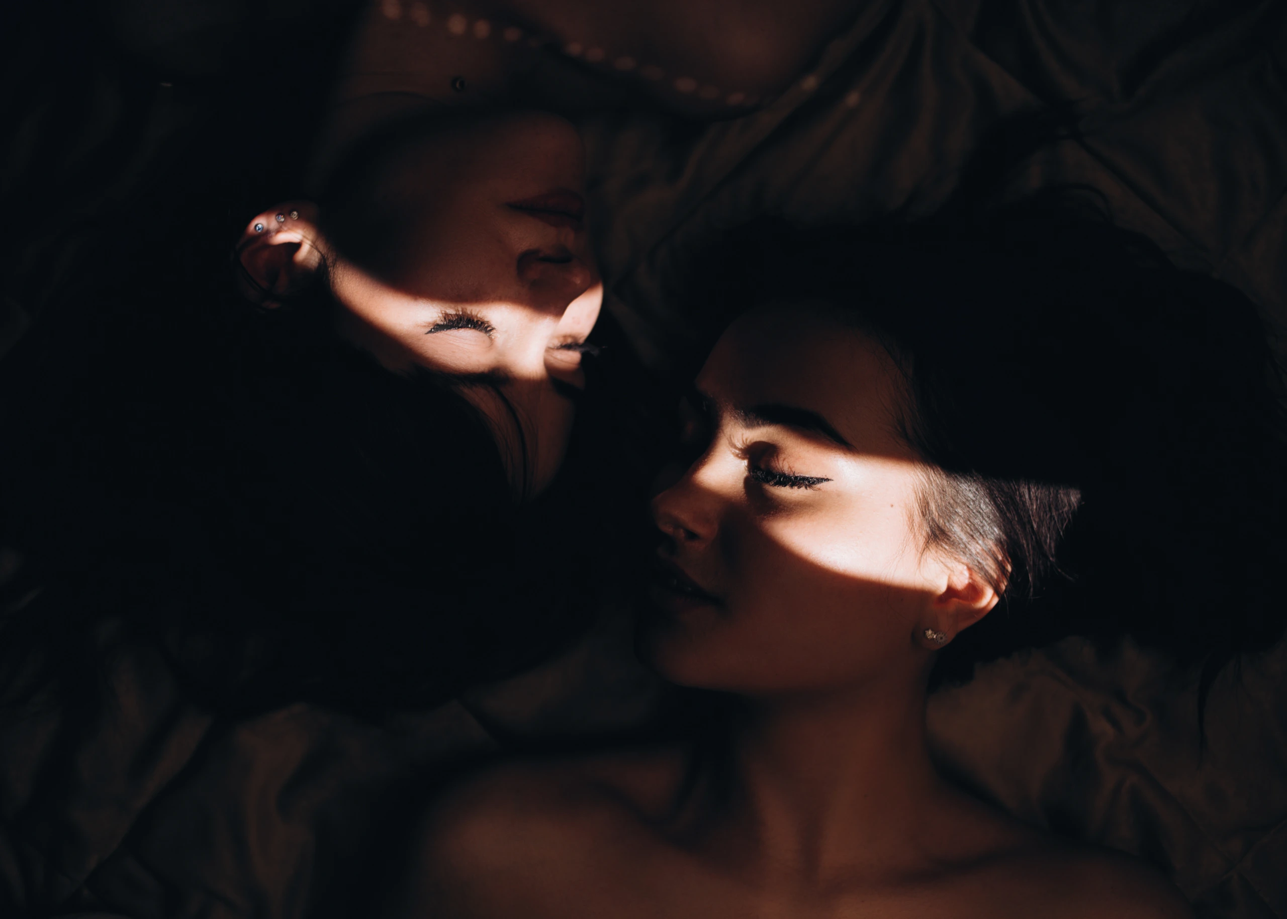Two women resting close together in warm light and shadow